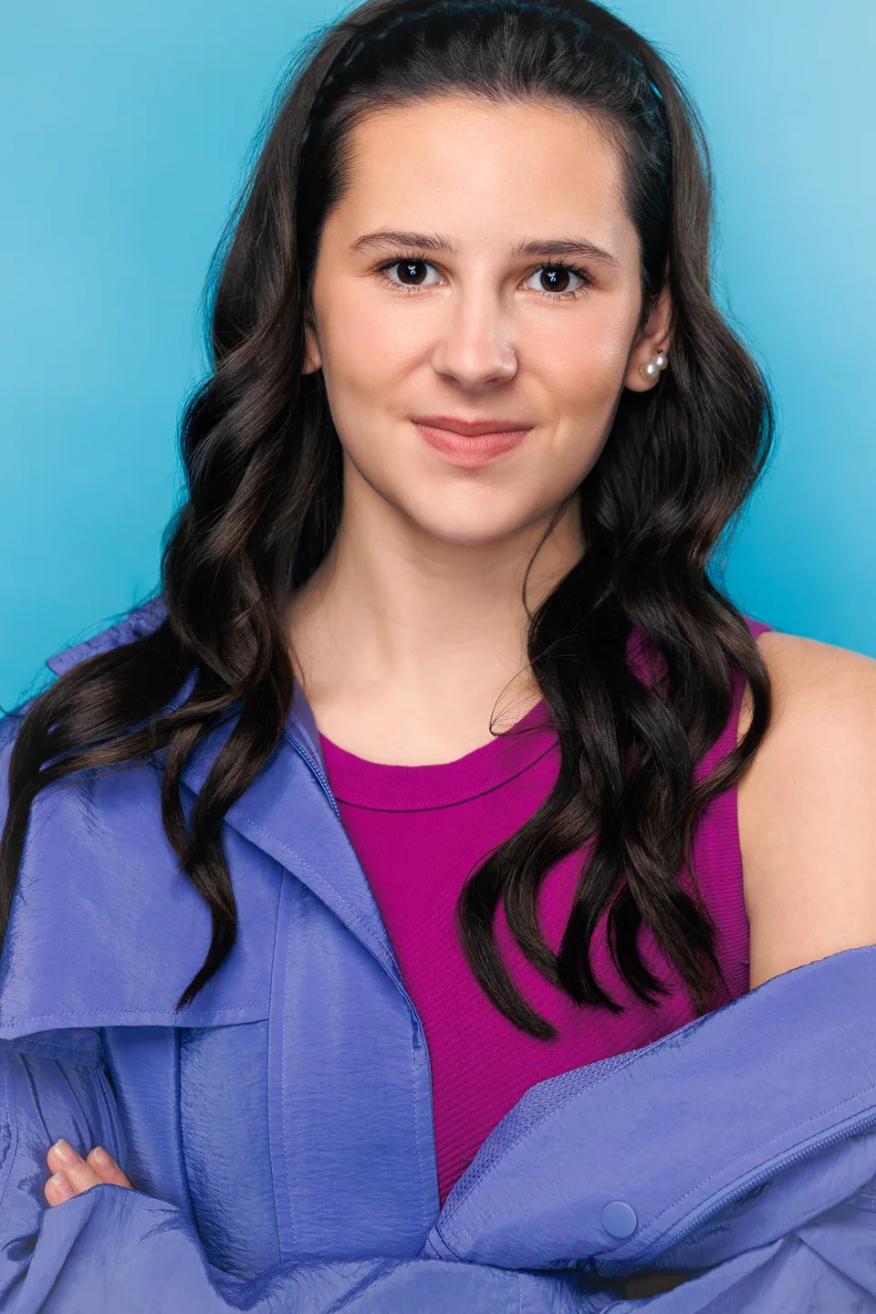 Ella in a fuchsia blouse against a blue studio background